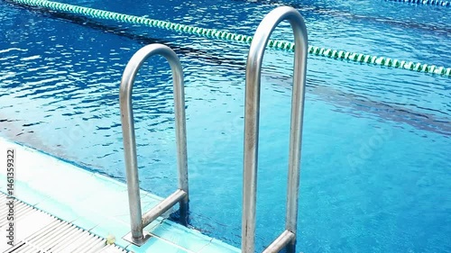 Swimming pool with pool ladder. Handrails to stairs leading to swimming pool