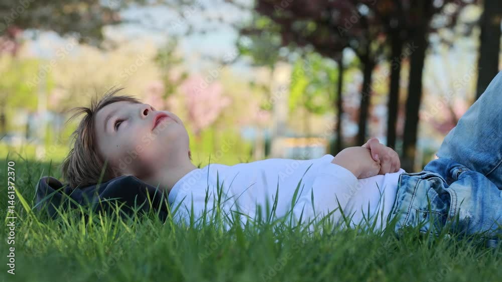 Portrait of cute stylish smiling toddler boy sitting in the grass in park Portrait of cute stylish smiling toddler boy sitting in the grass in park