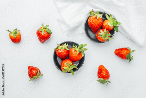 Fresh strawberries arranged in bowls on a white background in a kitchen setting