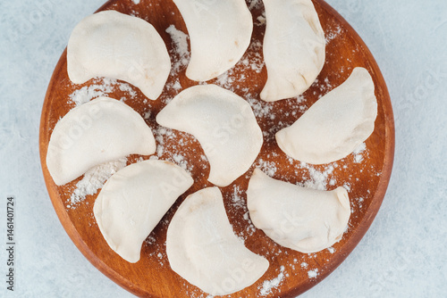 Obraz na płótnie Preparing homemade dumplings on a wooden board in a kitchen setting w salonie
