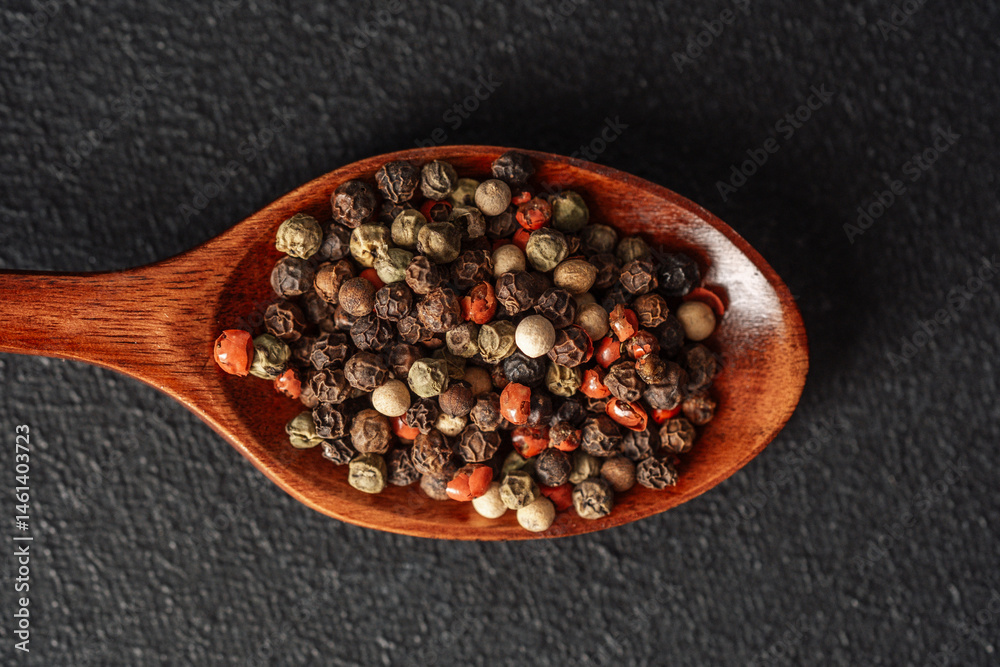 Variety of spices displayed on a wooden spoon on a dark background