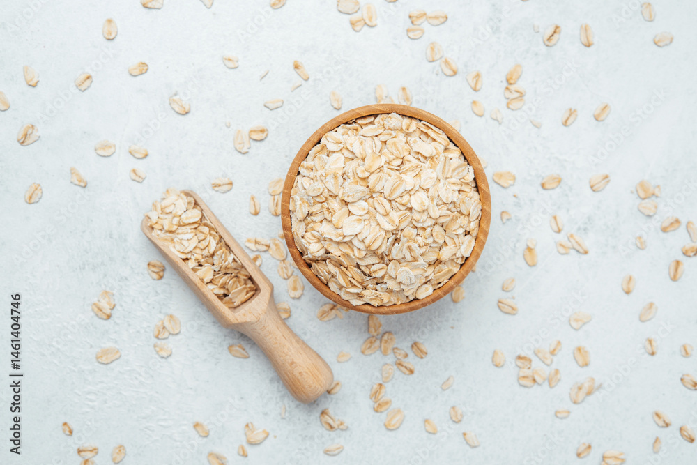 Healthy oats in a wooden bowl with a scoop on a light background