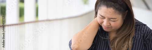Middle-aged, plus-size asian woman having neck and shoulder muscle stiffness or neck pain from overwork, office syndrome, muscle cramp