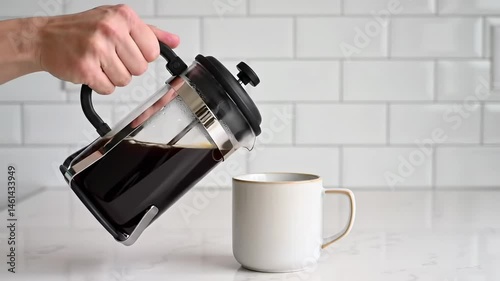 A Hand Pouring Hot Brewed Coffee from a French Press into a White Ceramic Mug on a Marble Kitchen Countertop, Capturing a Moment of Morning Ritual