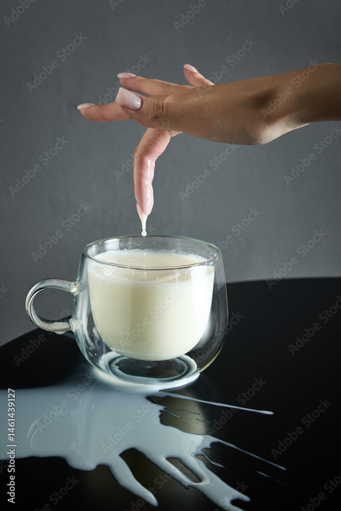 Organic milk, with drop dripping from fingertip into clear glass mug, natural goodness and appealing taste. Concept of drink, organic food, aesthetics, advertisement