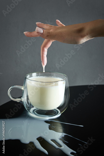 Obraz na płótnie Organic milk, with drop dripping from fingertip into clear glass mug, natural goodness and appealing taste. Concept of drink, organic food, aesthetics, advertisement w salonie