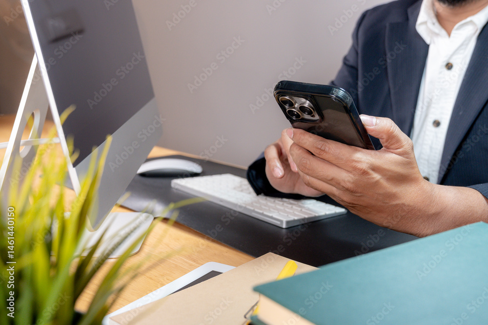 Fototapeta premium Partial view of a focused businessman multitasking, holding a phone to his ear while typing on a computer keyboard