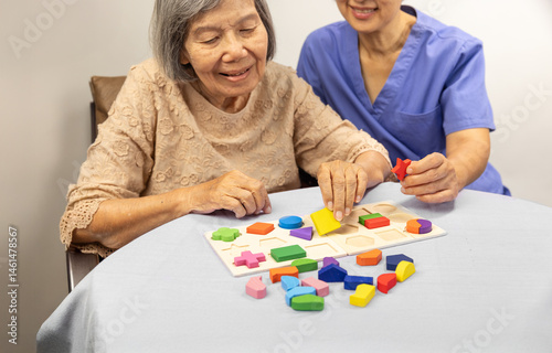 Caregiver and senior woman playing stringing beads game for dementia prevention