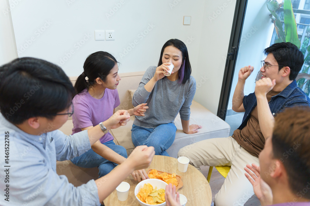 Fototapeta premium Group of friends enjoying snacks and drinks in a cozy indoor setting while engaging in lively conversation and activities