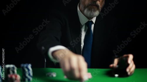 Middle-aged businessman drinking whiskey and placing poker bet, gambling