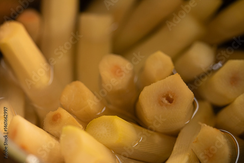 Obraz na płótnie High-resolution image of fresh bamboo shoots, peeled and sliced, submerged in water. Ideal for culinary and Asian cuisine themes. w salonie