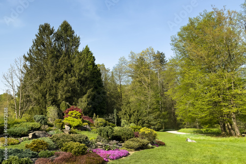 Bilde på lerret vibrant spring garden with vivid flowers, bushes, and manicured landscape in bright sunlight