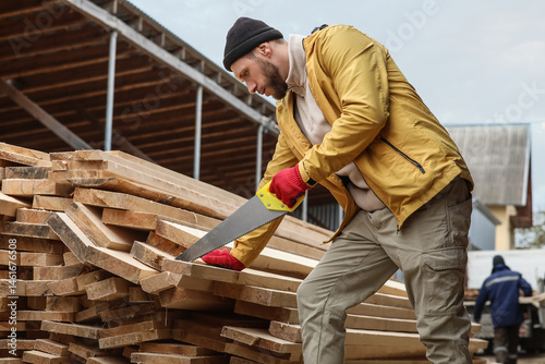 Male carpenter sawing woode...