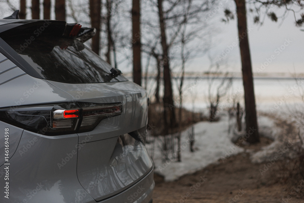 Obraz premium A white car is beautifully parked on a snowy road in the woods