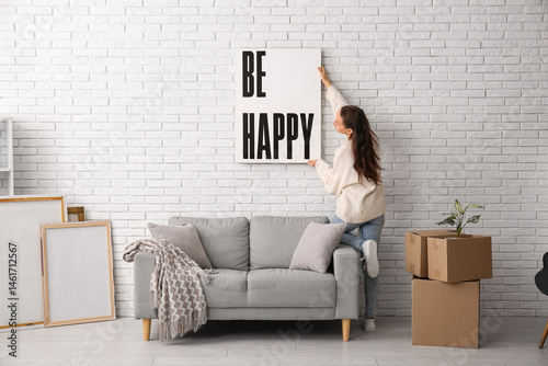 Young woman hanging poster ...