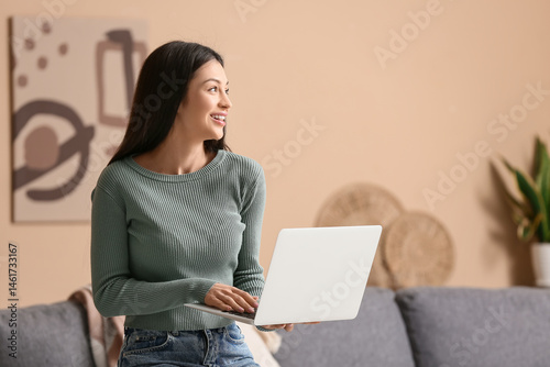 Smiling young woman using l...