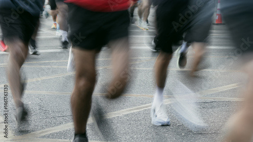 Blurred Legs of Runners Passing by on City Street During Professional Race – Running Concept