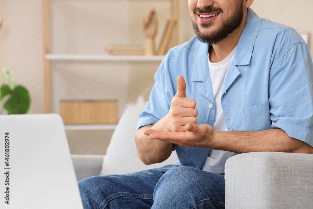 Fototapeta premium Young mute man using sign language during video call at home