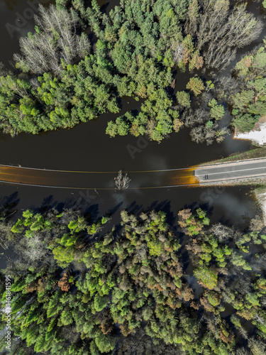 Obraz na płótnie Lake District swallow hole flooded as a result of the mining damage Pomorzany mine in Olkusz,Poland. Aerial drone view of flooded road. Forest submerged in a lake. Sunken sandpit with clear water w salonie