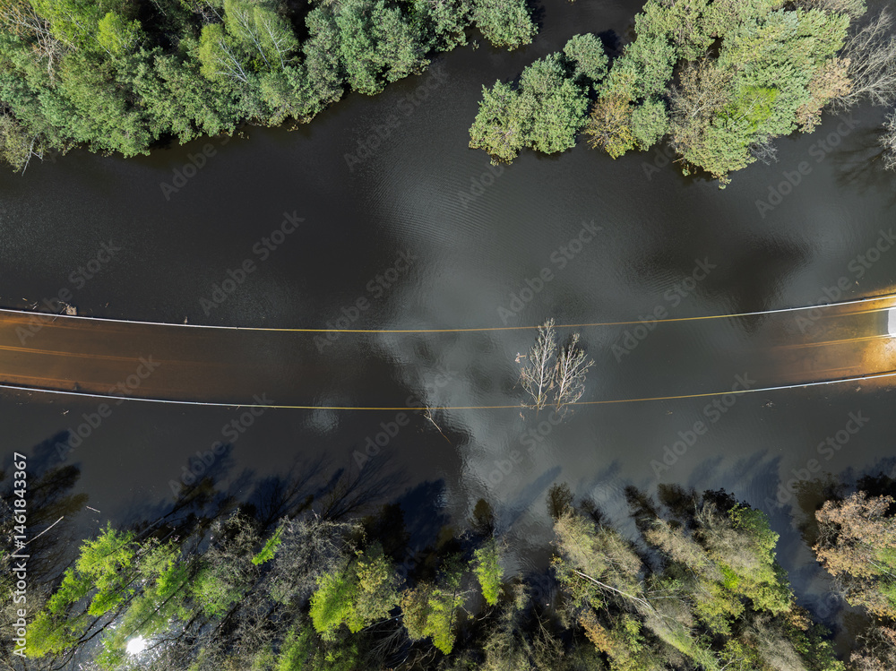 Lake District swallow hole flooded as a result of the mining damage Pomorzany mine in Olkusz,Poland. Aerial drone view of flooded road. Forest submerged in a lake. Sunken sandpit with clear water