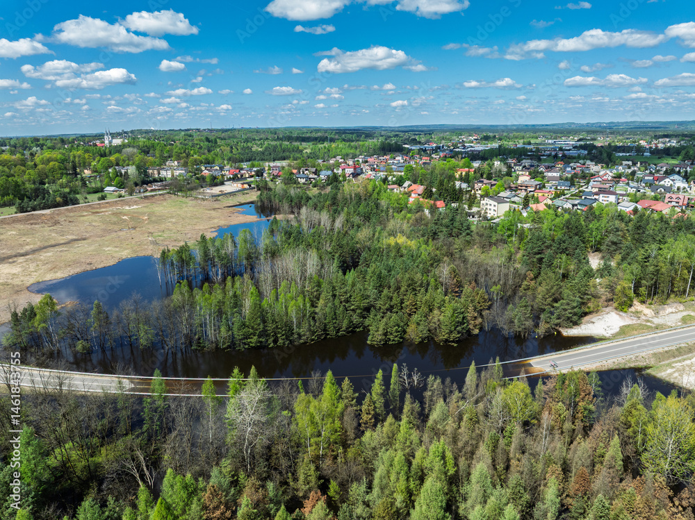 Lake District swallow hole flooded as a result of the mining damage Pomorzany mine in Olkusz,Poland. Aerial drone view of flooded road. Forest submerged in a lake. Sunken sandpit with clear water