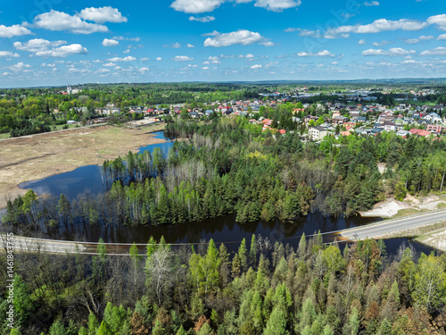 Lake District swallow hole flooded as a result of the mining damage Pomorzany mine in Olkusz,Poland. Aerial drone view of flooded road. Forest submerged in a lake. Sunken sandpit with clear water