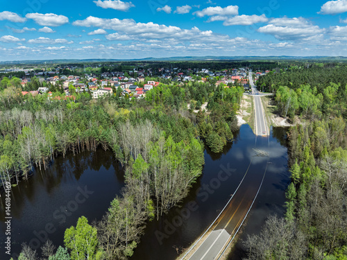 Obraz na płótnie Lake District swallow hole flooded as a result of the mining damage Pomorzany mine in Olkusz,Poland. Aerial drone view of flooded road. Forest submerged in a lake. Sunken sandpit with clear water w salonie