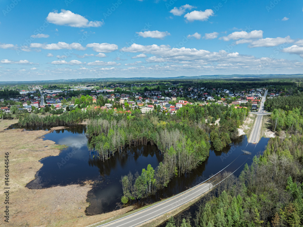 Lake District swallow hole flooded as a result of the mining damage Pomorzany mine in Olkusz,Poland. Aerial drone view of flooded road. Forest submerged in a lake. Sunken sandpit with clear water