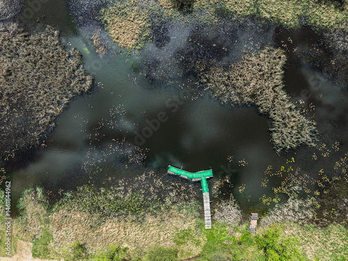 Obraz na płótnie Lake District swallow hole flooded as a result of the mining damage Pomorzany mine in Olkusz,Poland. Aerial drone view of flooded road. Forest submerged in a lake. Sunken sandpit with clear water w salonie