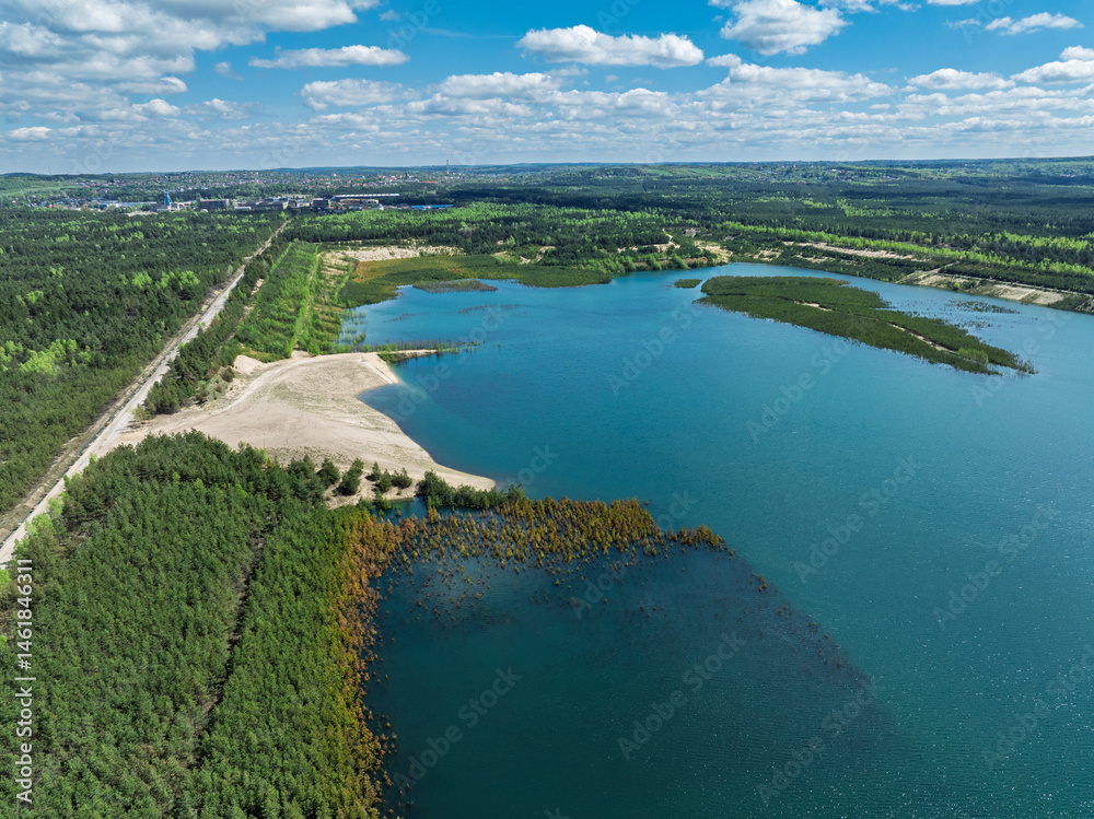 Lake District swallow hole flooded as a result of the mining damage Pomorzany mine in Olkusz,Poland. Aerial drone view of flooded sand pit. Forest submerged in a lake. Sunken sandpit with clear water