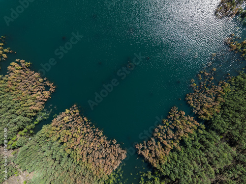 Obraz na płótnie Lake District swallow hole flooded as a result of the mining damage Pomorzany mine in Olkusz,Poland. Aerial drone view of flooded sand pit. Forest submerged in a lake. Sunken sandpit with clear water w salonie