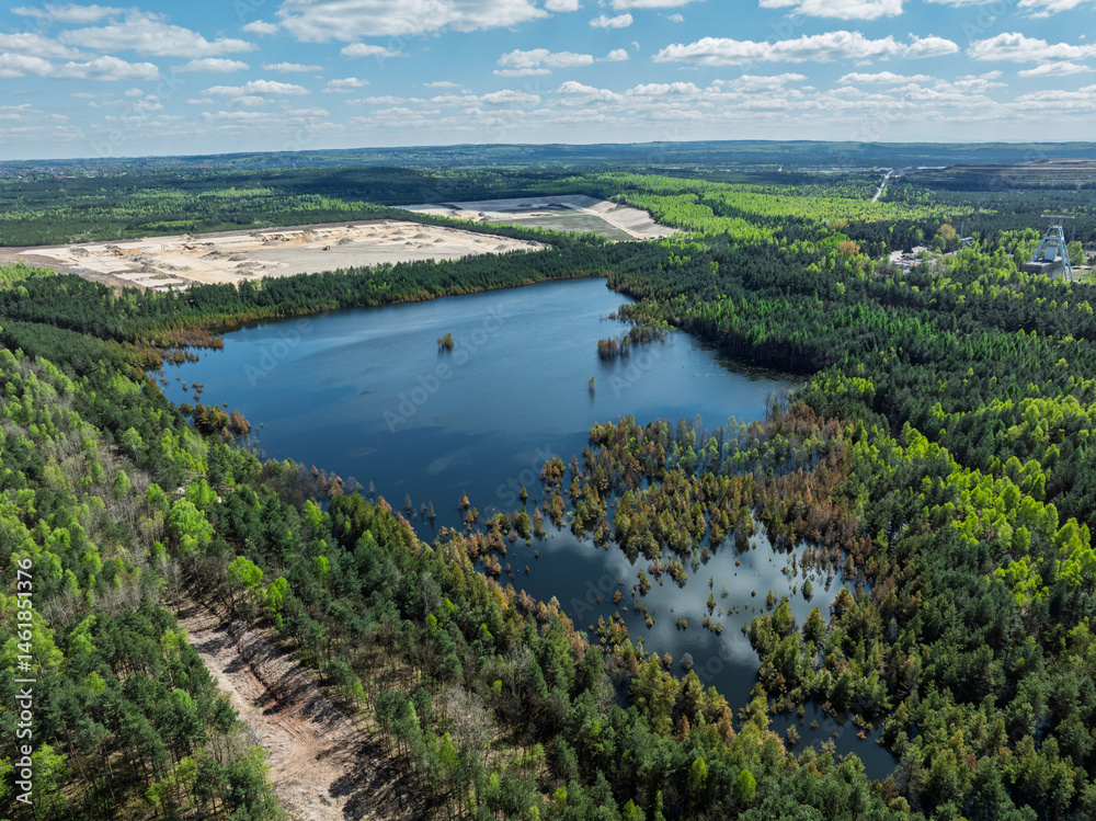 Lake District swallow hole flooded as a result of the mining damage Pomorzany mine in Olkusz,Poland. Aerial drone view of flooded sand pit. Forest submerged in a lake. Sunken sandpit with clear water