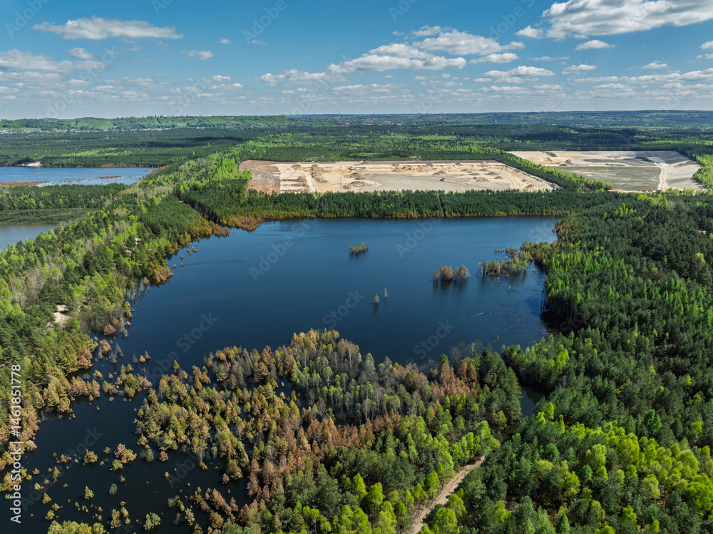 Lake District swallow hole flooded as a result of the mining damage Pomorzany mine in Olkusz,Poland. Aerial drone view of flooded sand pit. Forest submerged in a lake. Sunken sandpit with clear water