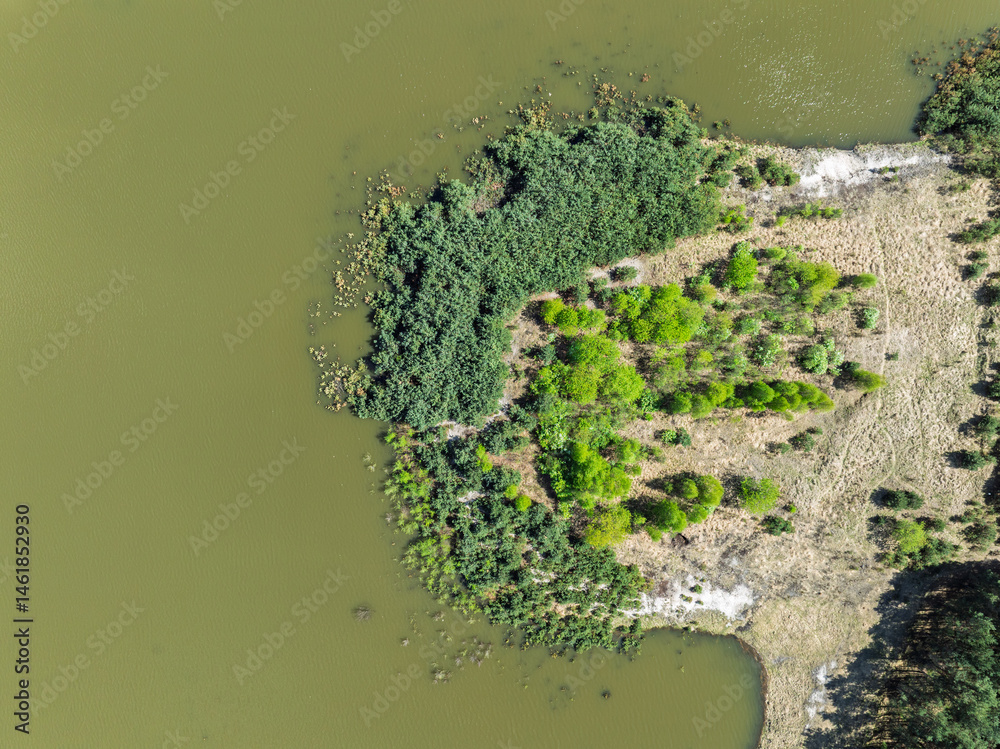 Lake District swallow hole flooded as a result of the mining damage Pomorzany mine in Olkusz,Poland. Aerial drone view of flooded sand pit. Forest submerged in a lake. Sunken sandpit with clear water