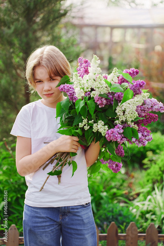Obraz na płótnie Young girl gathers lilac flowers in a vibrant garden during springtime w salonie
