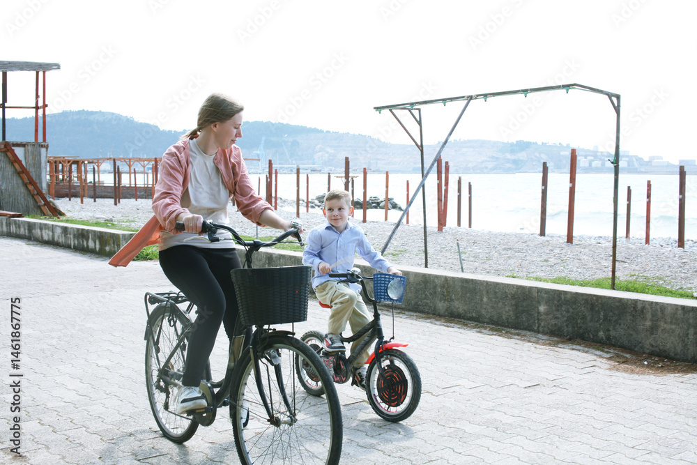 Obraz premium cute mother with children riding on bicycles on sea side, lifestyle people