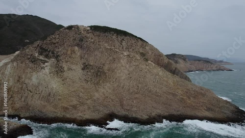 rugged cliffs with crashing waves under overcast sky at UNESCO Global Geopark in Hong Kong photo