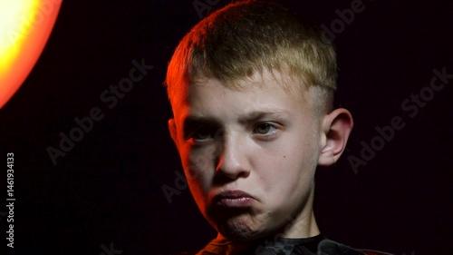 haircut of a young boy of the European region in a dark room in red light with a hair clipper
