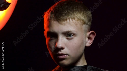 haircut of a young boy of the European region in a dark room in red light with a hair clipper