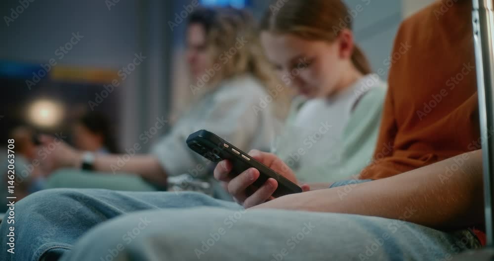 Crowded International Airport Terminal: Close Up of Teenagers Using Phone, Scrolling Social Media Content. Diverse Passengers Sitting in Departure Lounge of Airline Hub, Waiting for Airplane Flight.