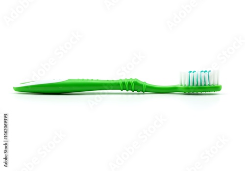 A green toothbrush with white and blue bristles lying on a white surface in a horizontal view