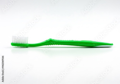 A close up shot of a green toothbrush with white bristles on a white surface in a horizontal position