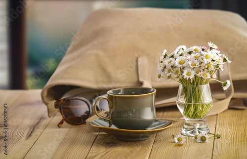 Elegant composition with daisy flowers and women's bag on wooden table with cozy background. Copy space for text or product. Mother's Day, Women's Day, birthday greeting or spring design project card.