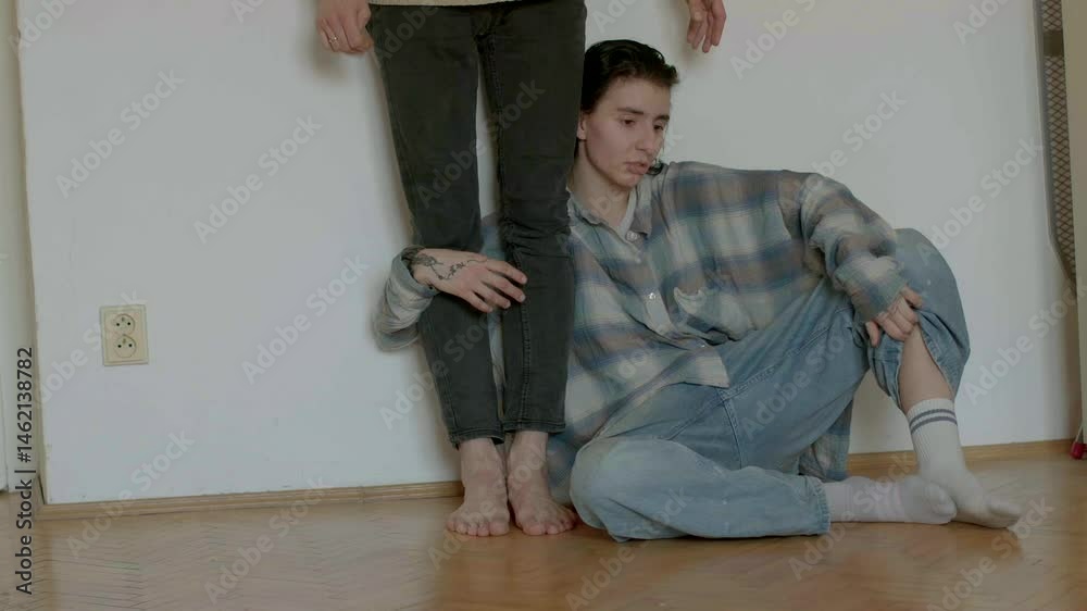 In a simplistic indoor area featuring wooden flooring, two figures engage in meaningful interaction