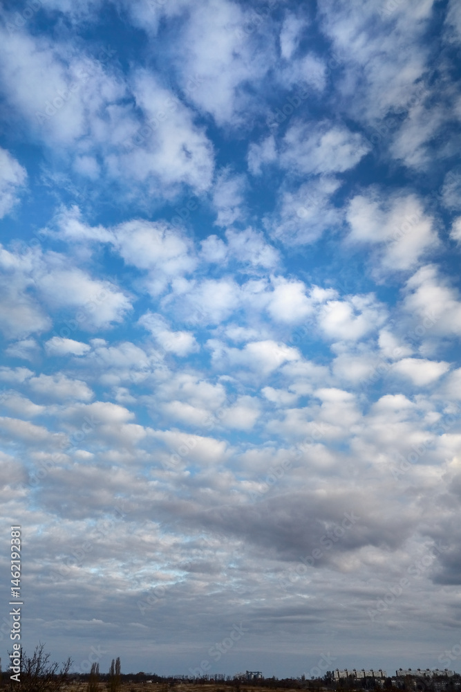 A cloud pattern of white clouds in the blue sky above the earth, featuring beautiful altocumulus clouds in a vertical frame. A cloud pattern of white clouds in the blue sky above the earth, featuring beautiful altocumulus clouds in a vertical frame.