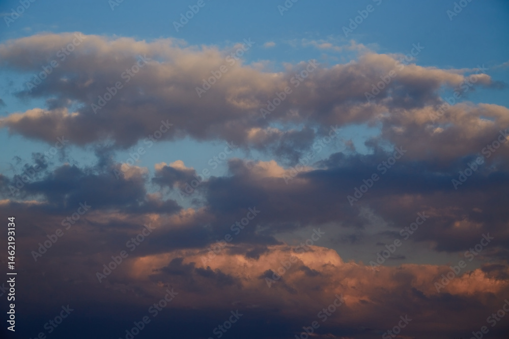 Obraz premium The evening sun paints cumulus clouds in warm orange-pink tones. This shot symbolizes completion, peace, and harmony. Suitable for themes of sunsets, love, and goodbyes.