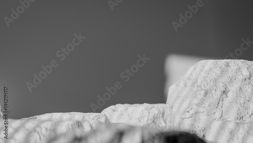 Bottle of perfume is shown on a rocky surface. The bottle is black and has a black cap. The bottle is placed on a rock, and the rock is surrounded by other mossy rocks. Premium photo 3d render.