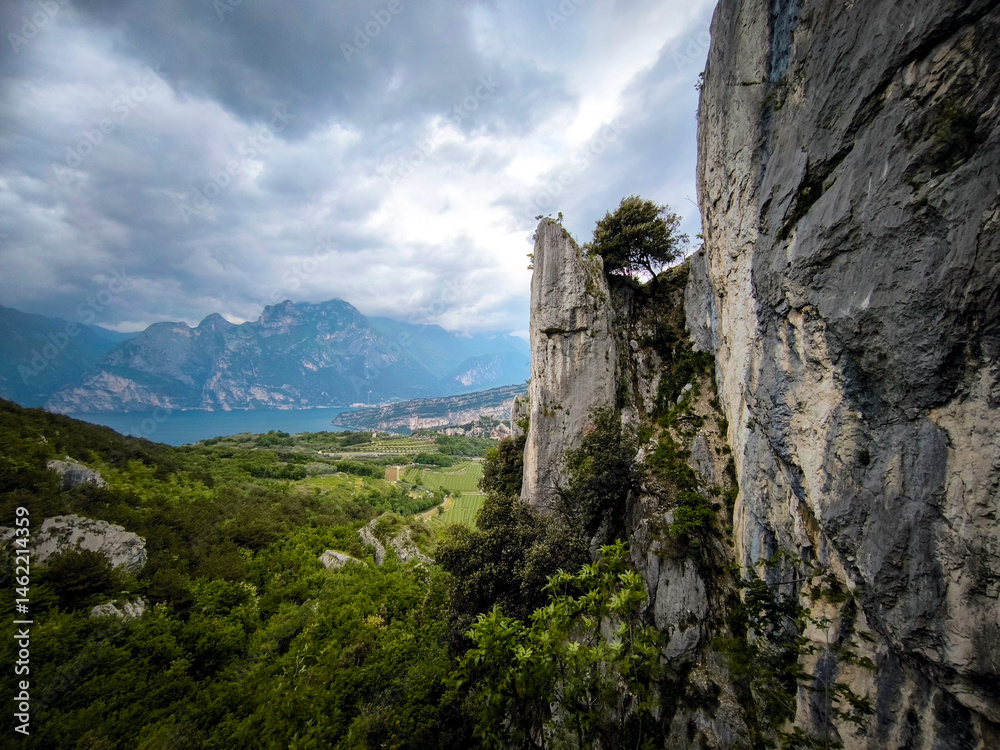 Fototapeta premium View From The Nago Climbing Base Camp In Italy, Overlooking The Garda Lake With Rocky Cliffs And Lush Greenery