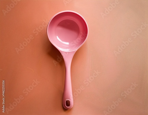 aesthetic overhead view of a pink ladle against a textured peach and coral colored background showcasing minimalist kitchen utensils for modern home decor