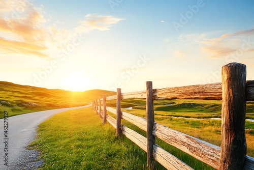 Scenic Sunset Over Rolling Green Hills and Wooden Fence alongside Country Road